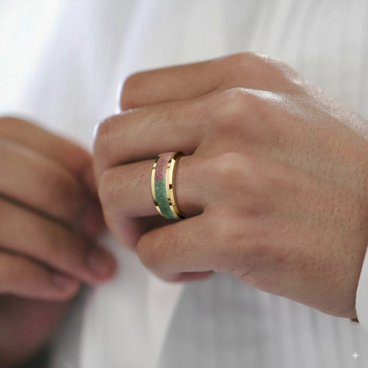 Close-up of a hand wearing a gold ring with a green stone on a white background