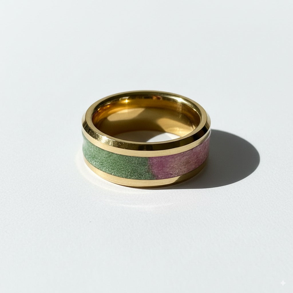Gold ring with green and pink inlay on a white background