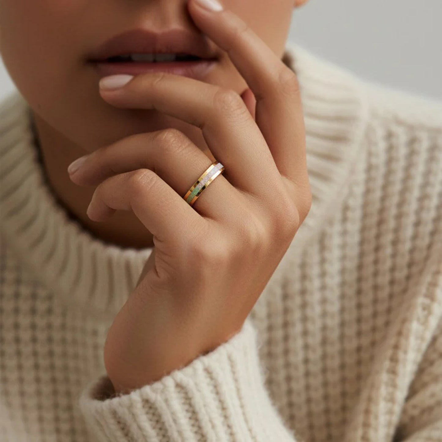 Close-up of a hand wearing a ring with a neutral background