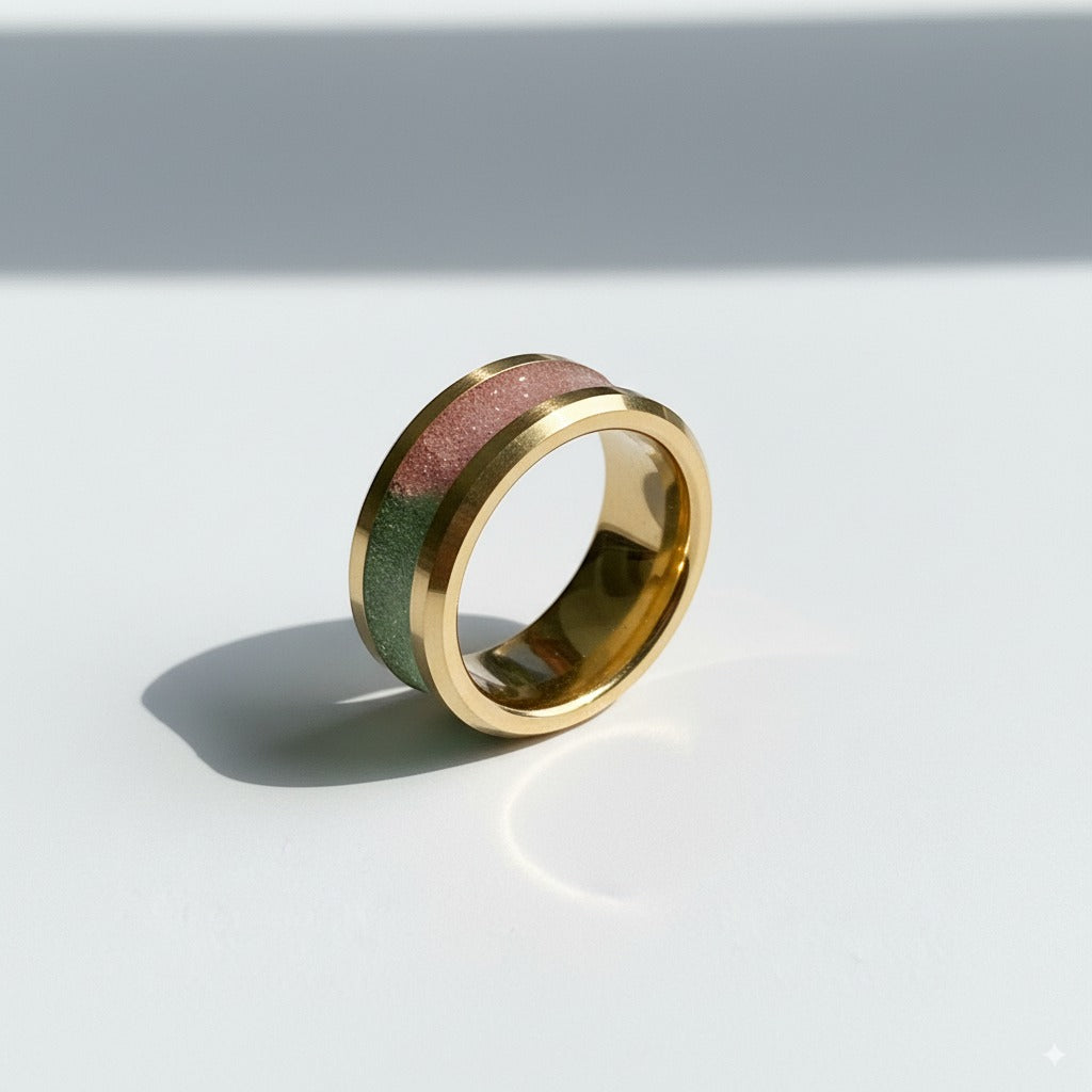 Gold ring with a pink and green inlay on a white background
